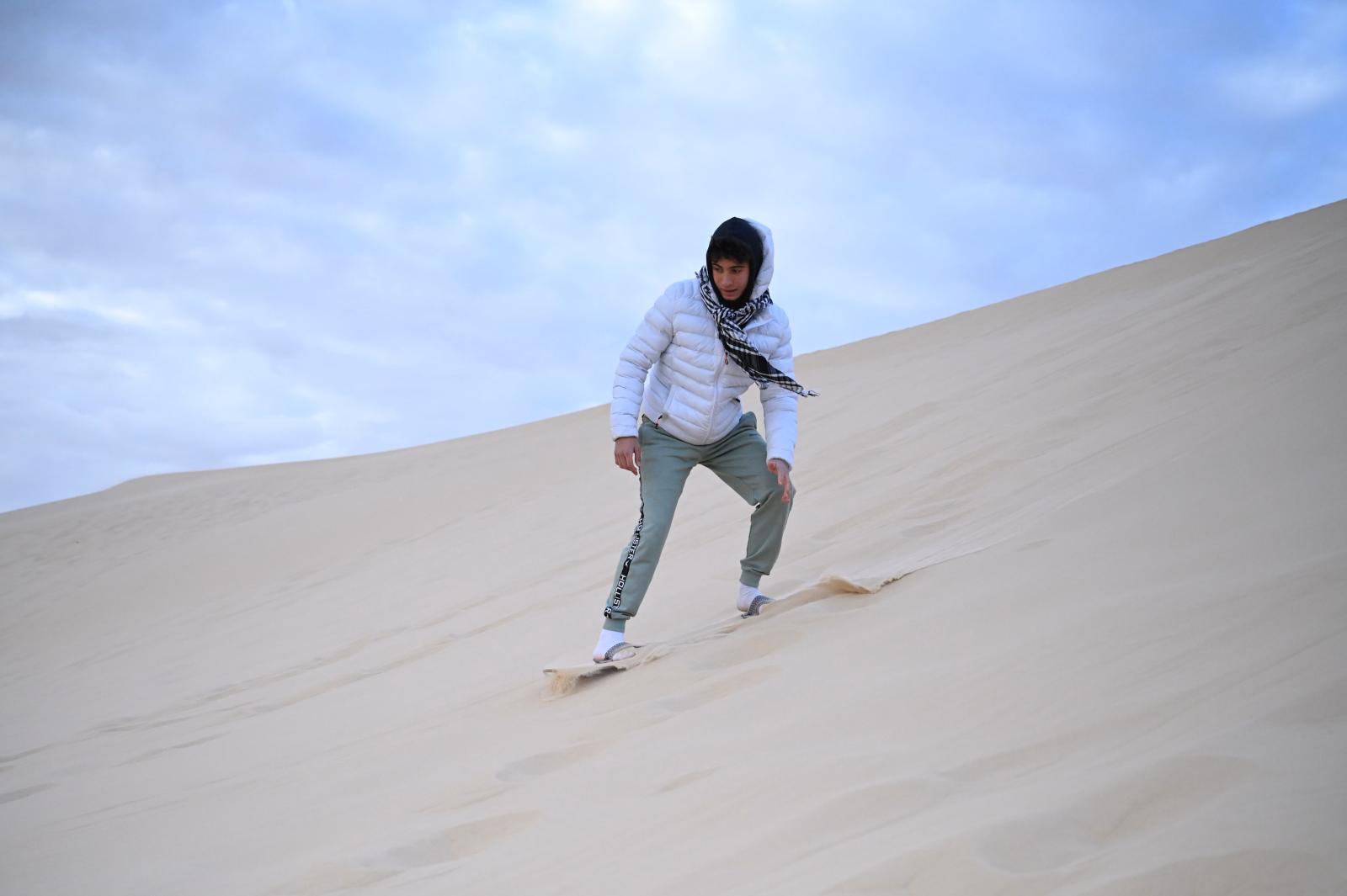 Sandboarding auf einer hohen Düne in der Wüste