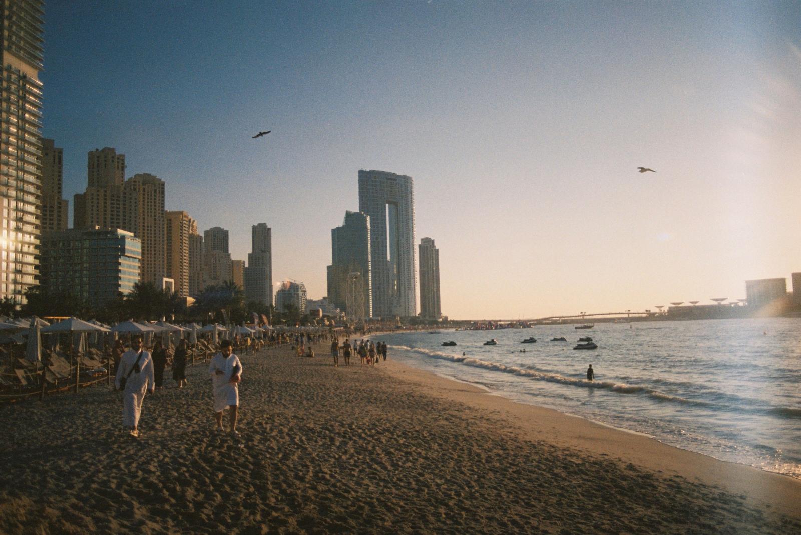 Sandstrand in Dubai mit türkisblauem Wasser und Skyline