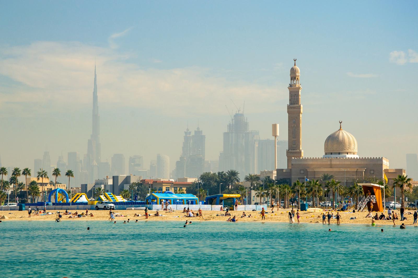 Breiter Sandstrand in Dubai mit Skyline im Hintergrund