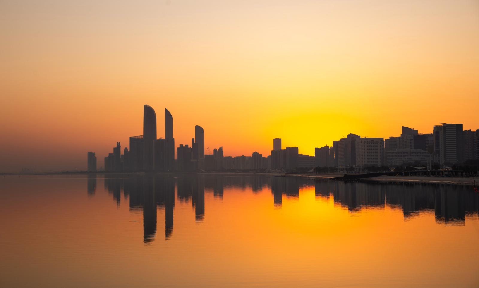 Abu Dhabi Panorama mit Skyline, Meer und Palmen bei Abendlicht