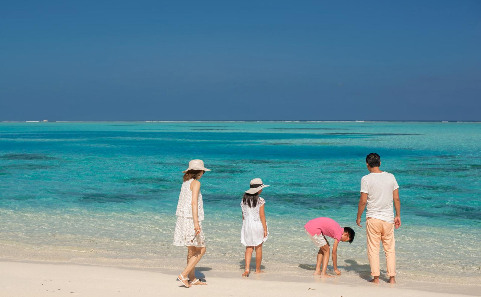 Urlauber am flachen, warmen Wasser einer Maledivenlagune