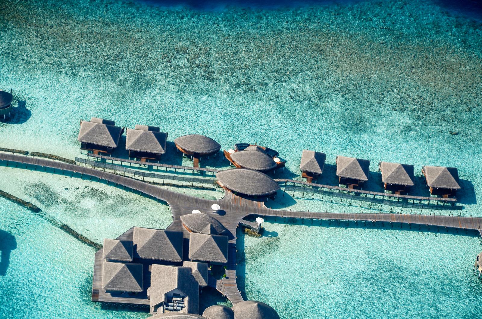 Panorama eines exklusiven Malediven-Resorts mit weißen Stränden, türkisfarbener Lagune und eleganten Wasservillen