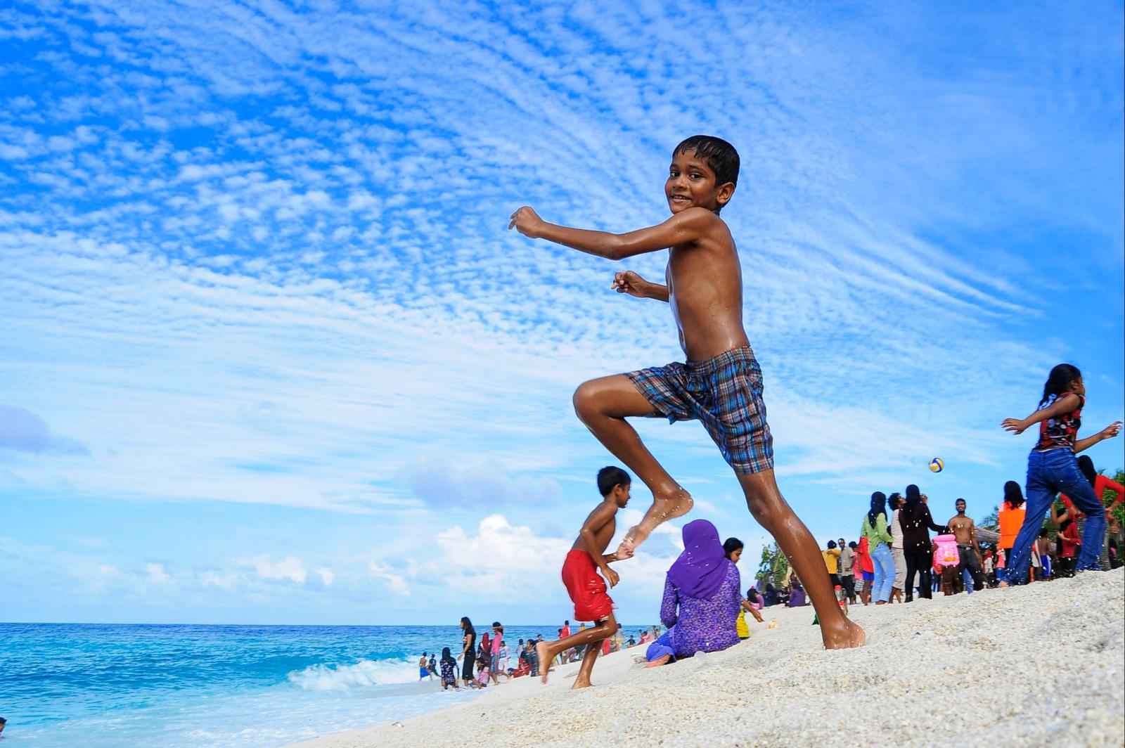  Kinder spielen unter Aufsicht am Strand einer tropischen Insel]
