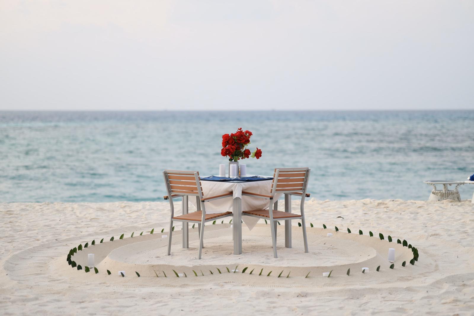 Romantisch gedeckter Tisch am Strand mit Blick auf das Meer bei Sonnenuntergang