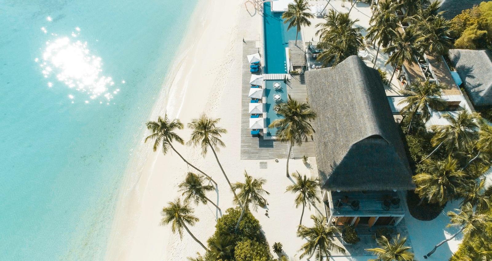 Elegante Villa am weißen Sandstrand mit Palmen und türkisfarbenem Wasser