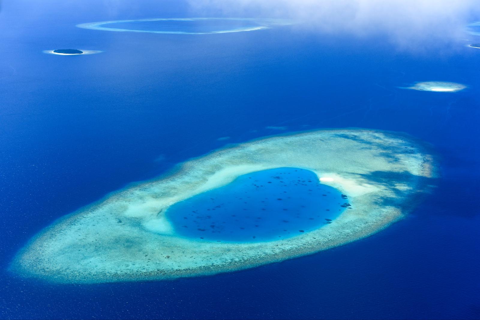 Luftaufnahme eines Atolls mit Korallenriff, Lagune und kleinen Inseln