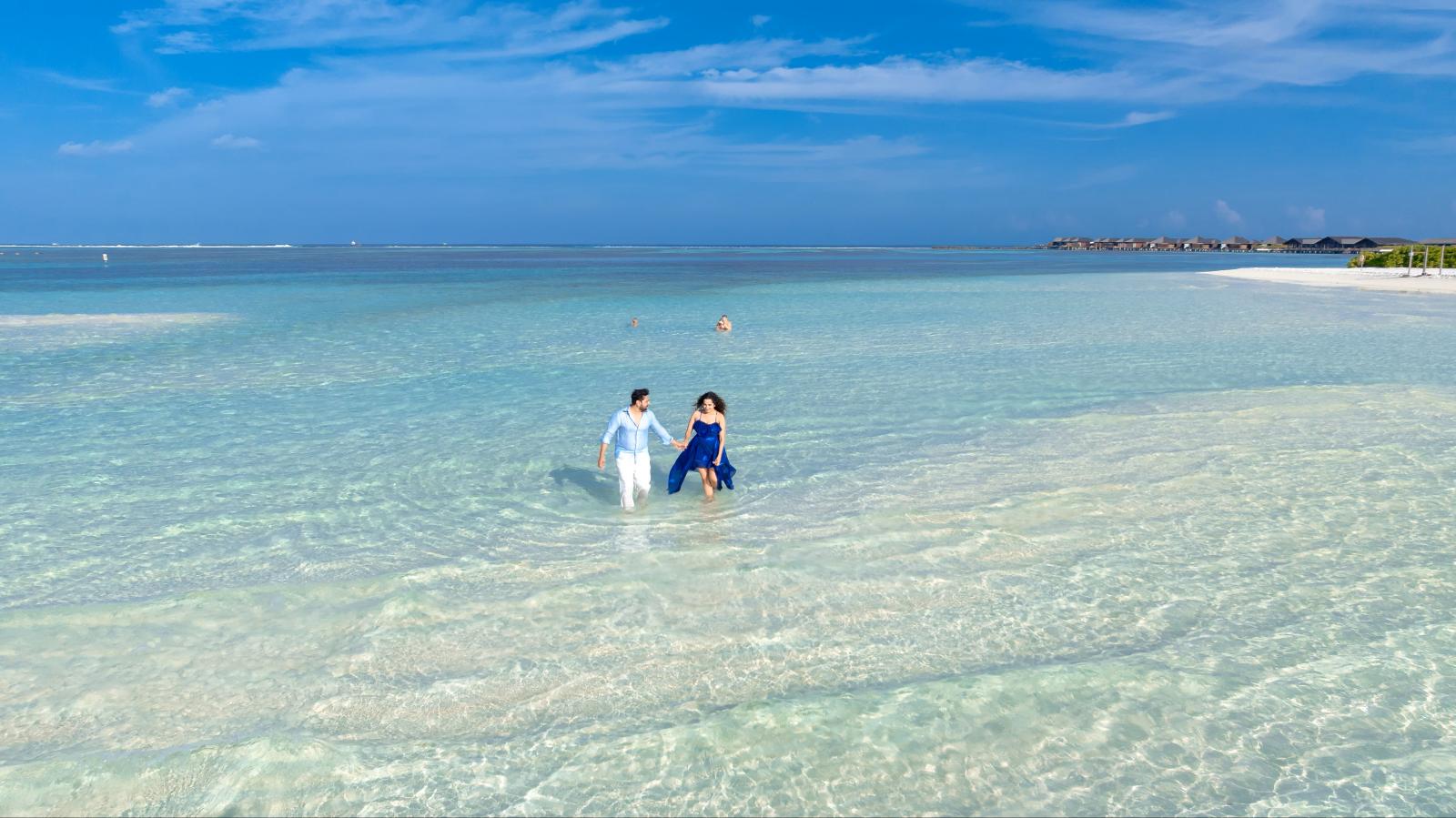 Paar entspannt an einem weißen Sandstrand vor türkisblauem Meer