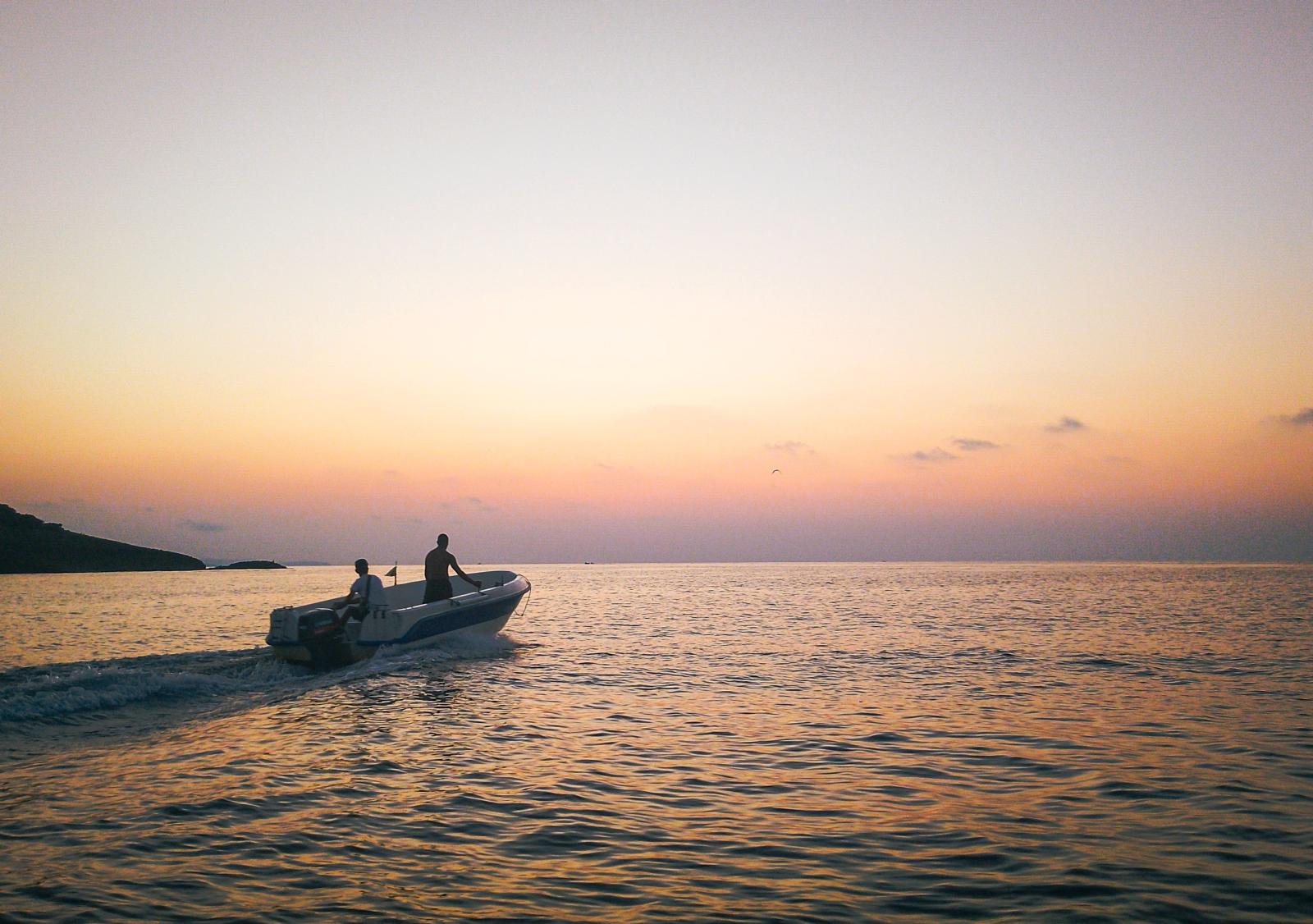 Paar auf einem Boot bei Sonnenuntergang über dem Indischen Ozean]