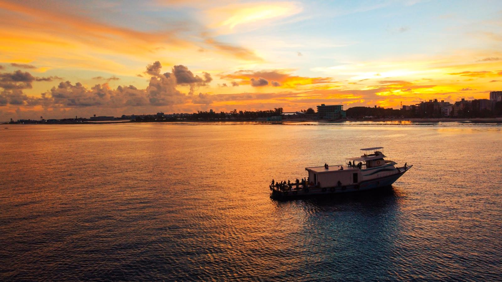 Traditionelles Ausflugsboot vor einer Insel im warmen Abendlicht