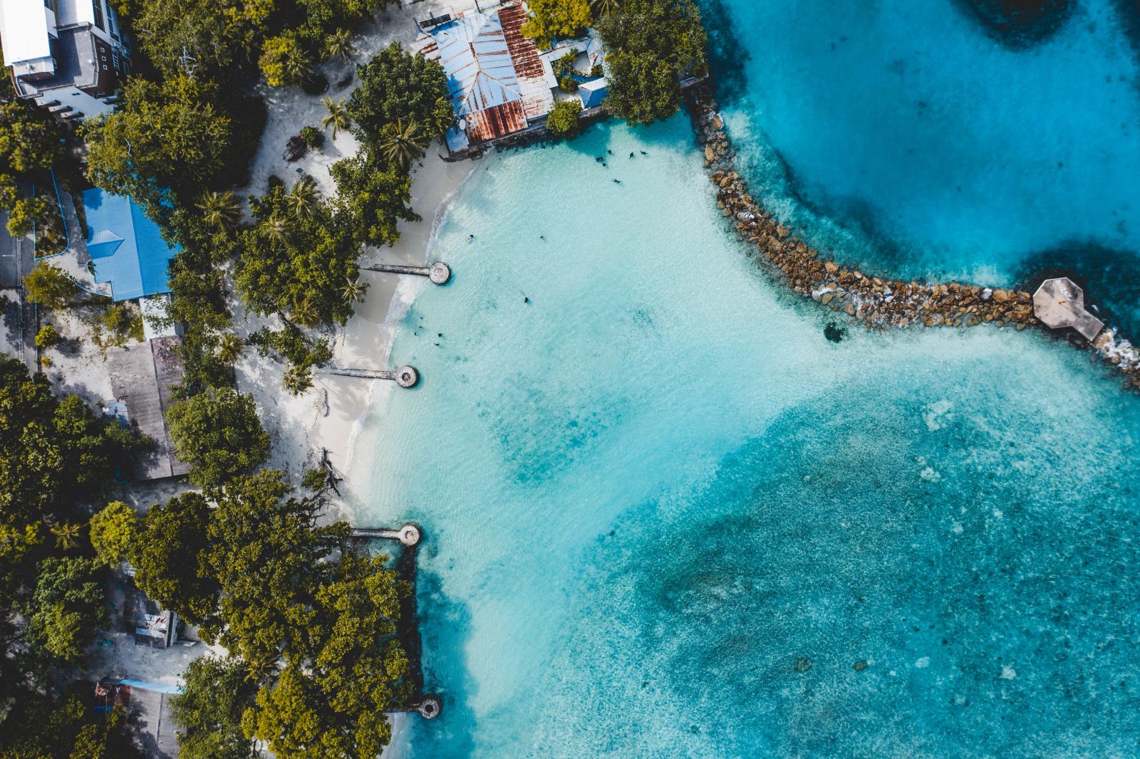 Luftaufnahme einer tropischen Malediveninsel mit hellem Strand und Lagune