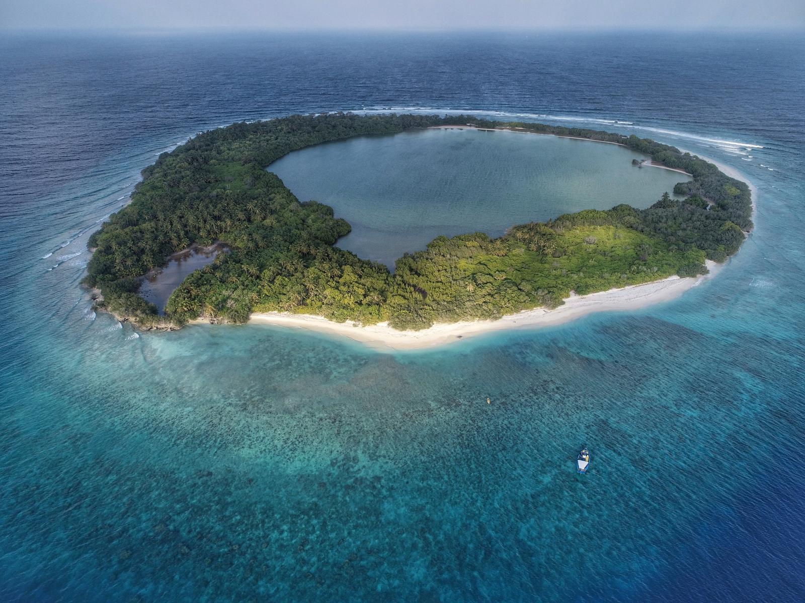 Luftaufnahme eines Atolls mit türkisblauer Lagune und Korallenriffen