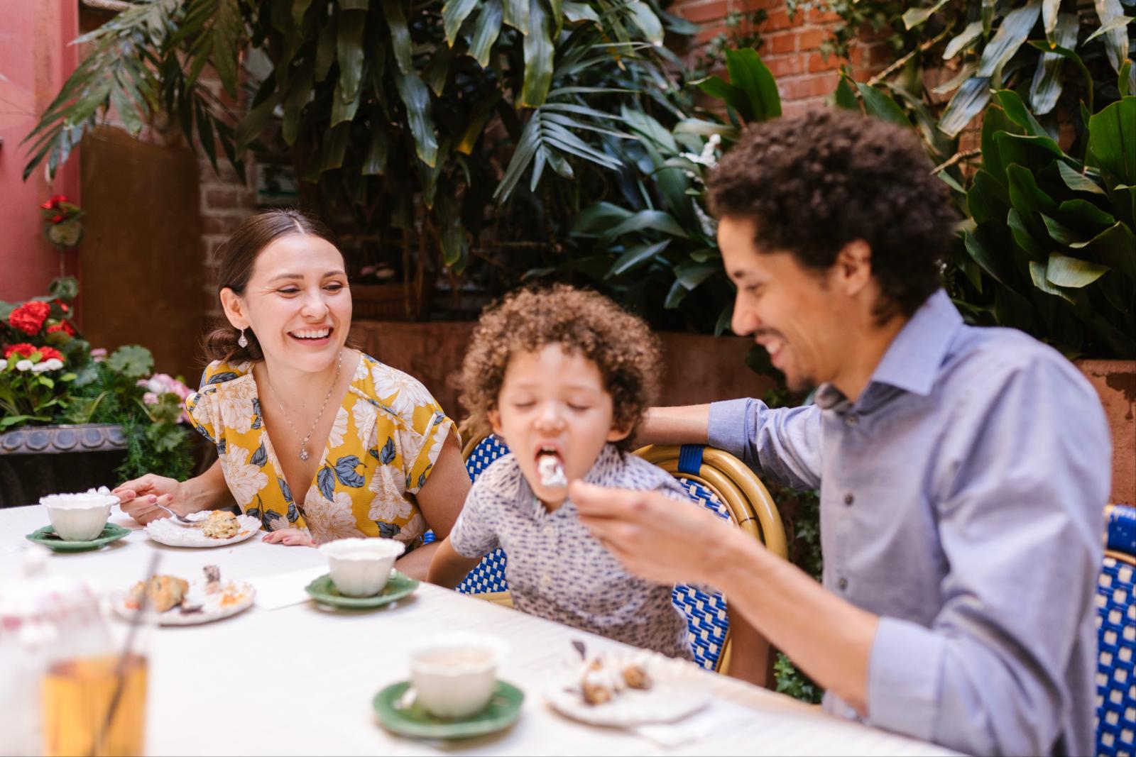 Familie sitzt gemeinsam beim Essen auf einer offenen Restaurantterrasse
