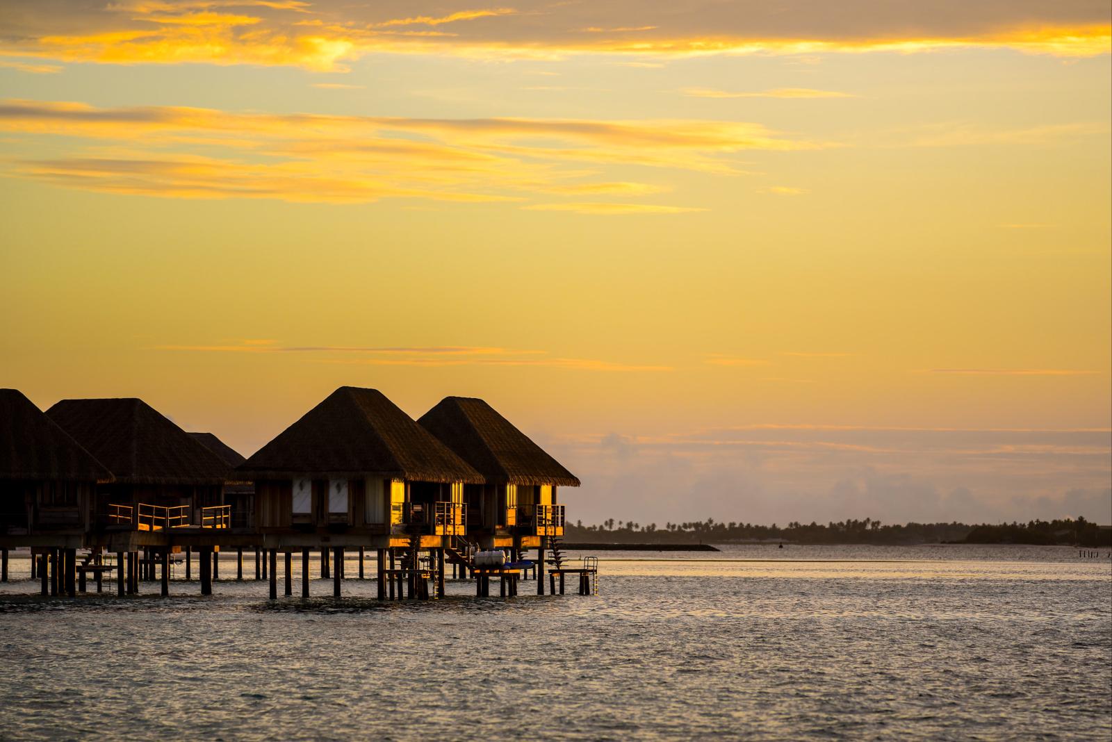  Wasserbungalows bei Sonnenuntergang mit ruhigem Meer und warmem Abendlicht