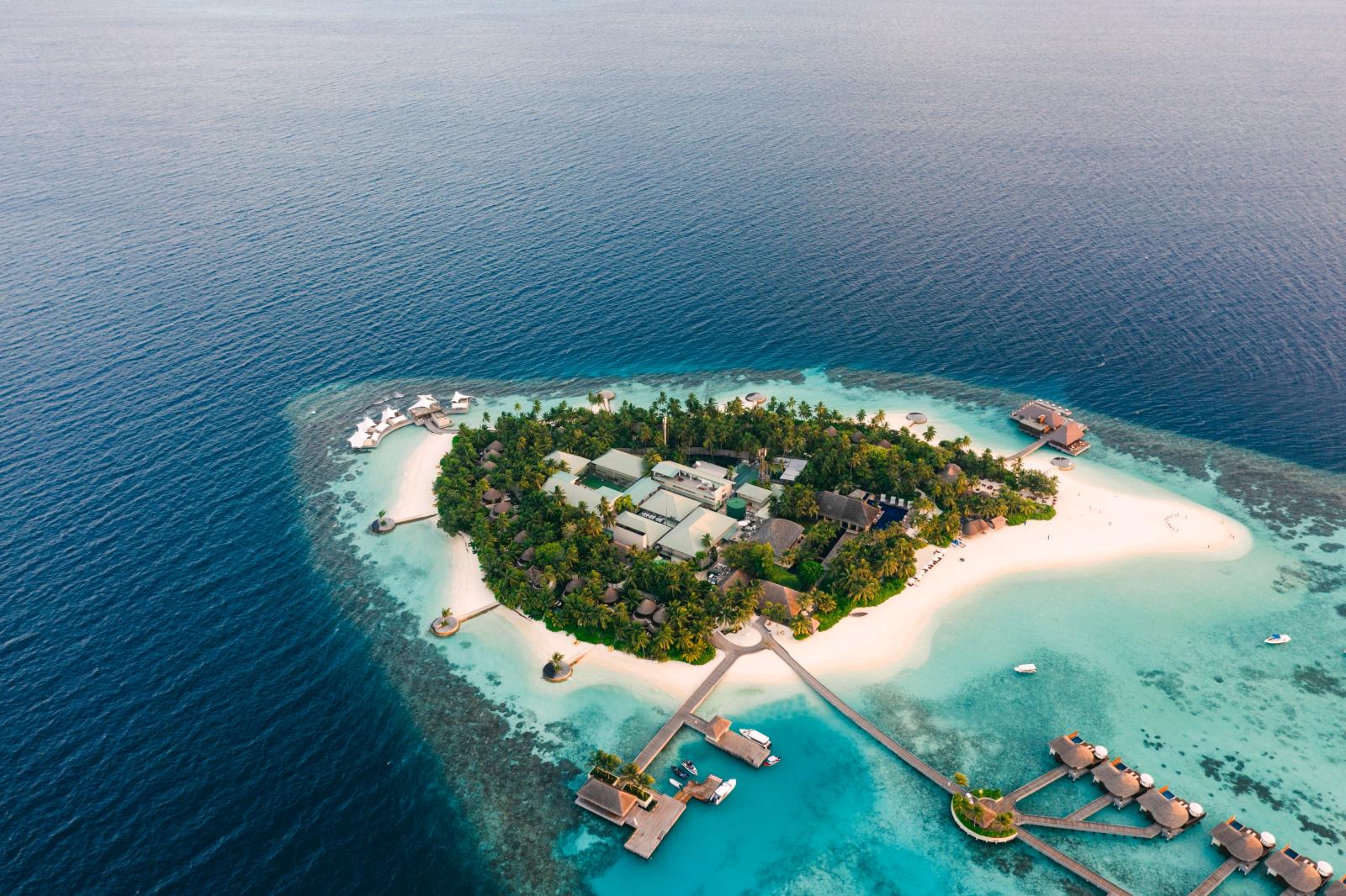 Luftaufnahme einer exklusiven Resortinsel mit türkisblauem Wasser und weißem Sandstrand