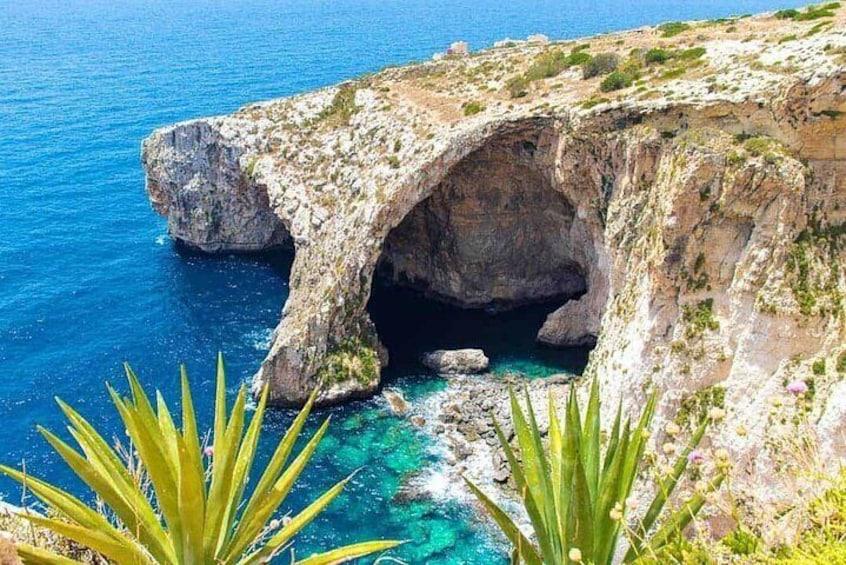 Entdecken Sie die atemberaubende felsige Küste und das azurblaue Wasser von Mgarr, Malta, mit diesem malerischen Höhlenblick.