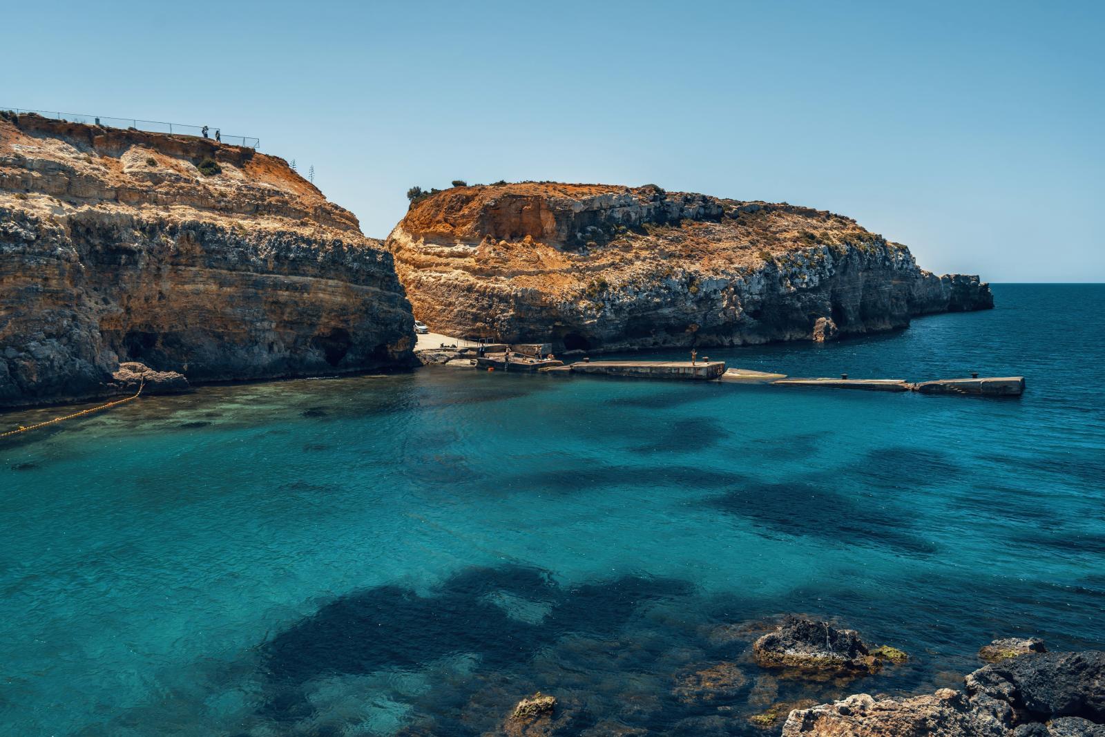 Badebucht auf Malta mit felsiger Küste, klarem Wasser und Sonnenschein