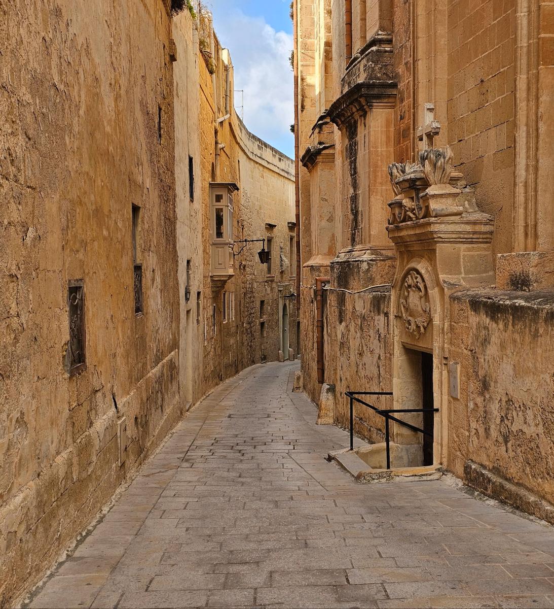 Historische Gasse in Mdina mit hellen Kalksteinfassaden und traditionellen Holztüren