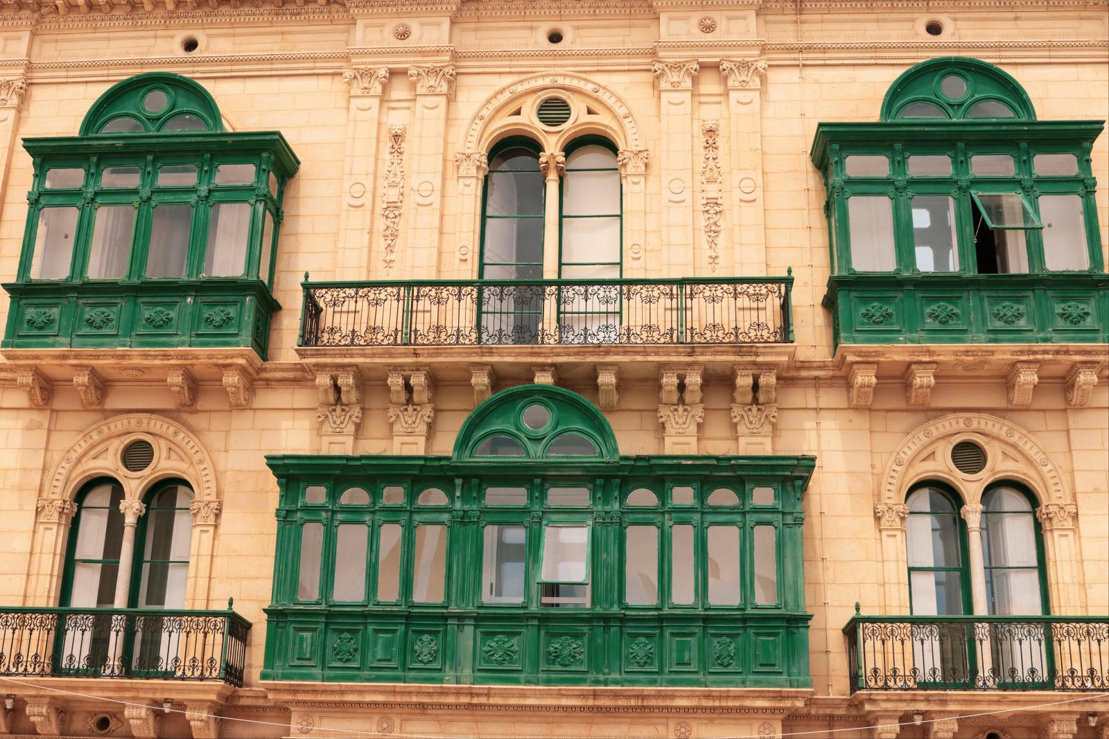 Faszinierende Fassade mit grünen Balkonen und verzierter Renaissance-Architektur in Valletta, Malta.