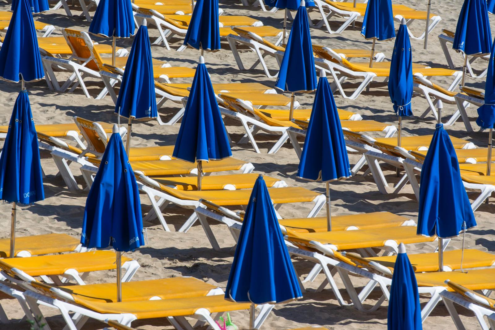 Strandliegen und Sonnenschirme an einem Sandstrand auf Malta]