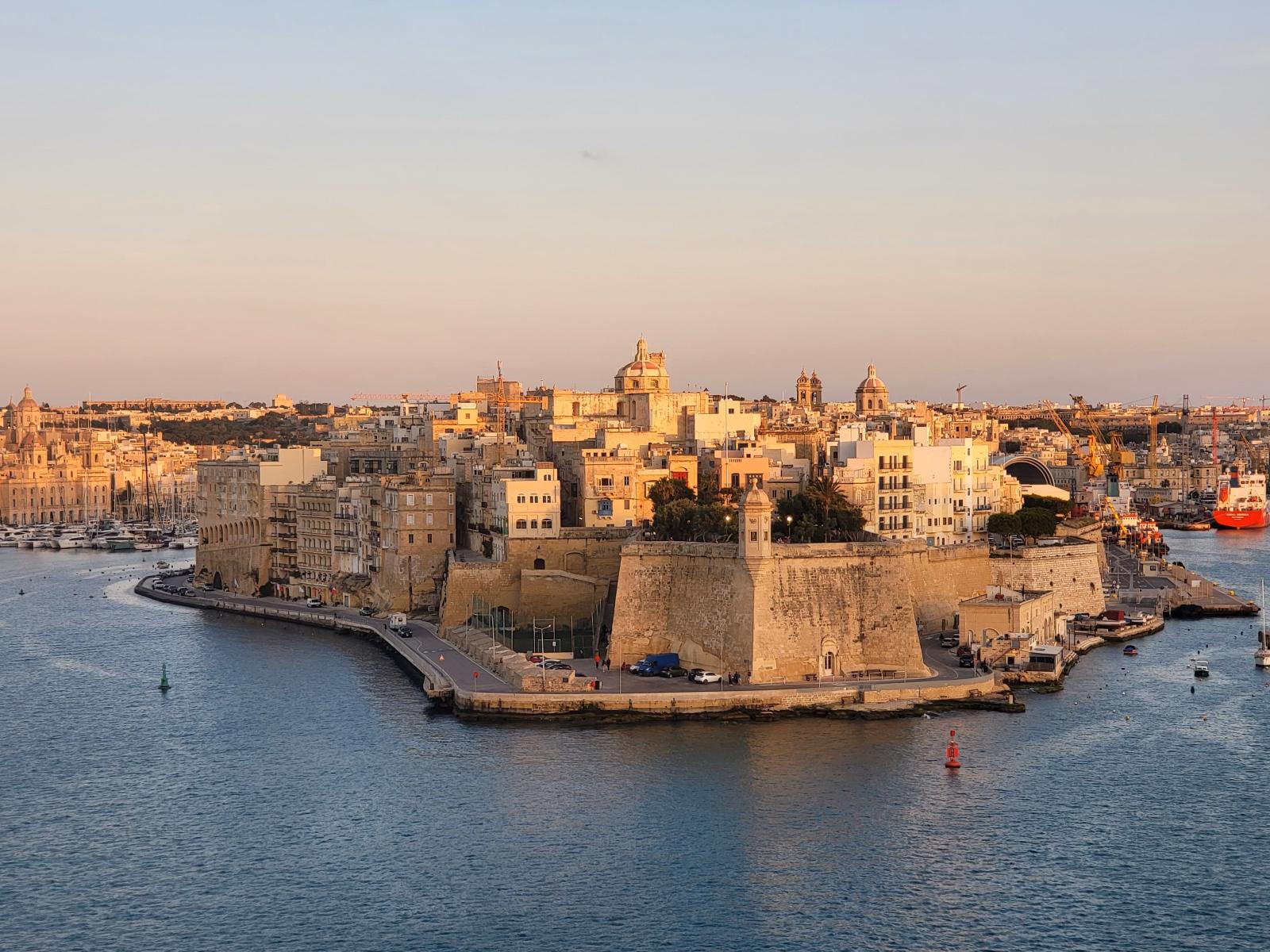 Sonnenuntergang über einer maltesischen Bucht mit mediterraner Küstenlandschaft