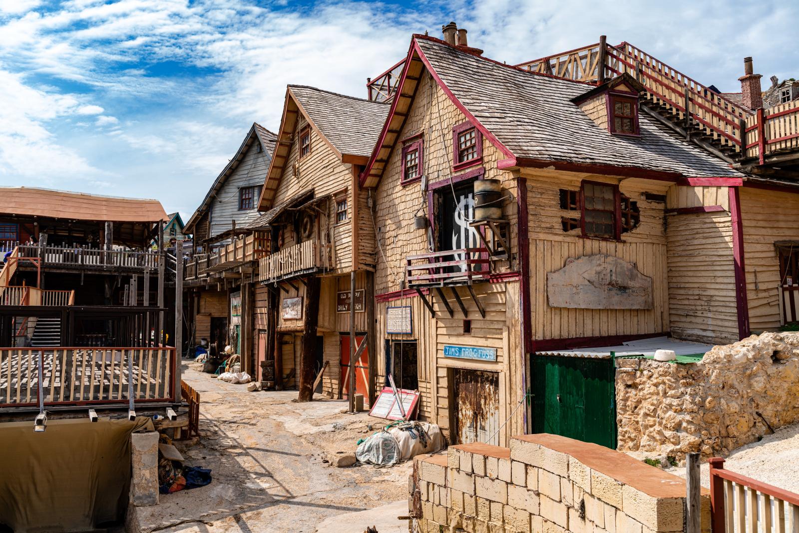 Malerische Aussicht auf Popeye Village, Mellieħa, Malta, mit rustikaler Holzarchitektur an einem sonnigen Tag.