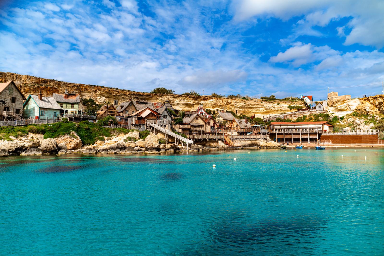 Bezaubernder Blick auf ein Küstendorf auf Malta mit azurblauem Wasser und lebendiger Architektur.