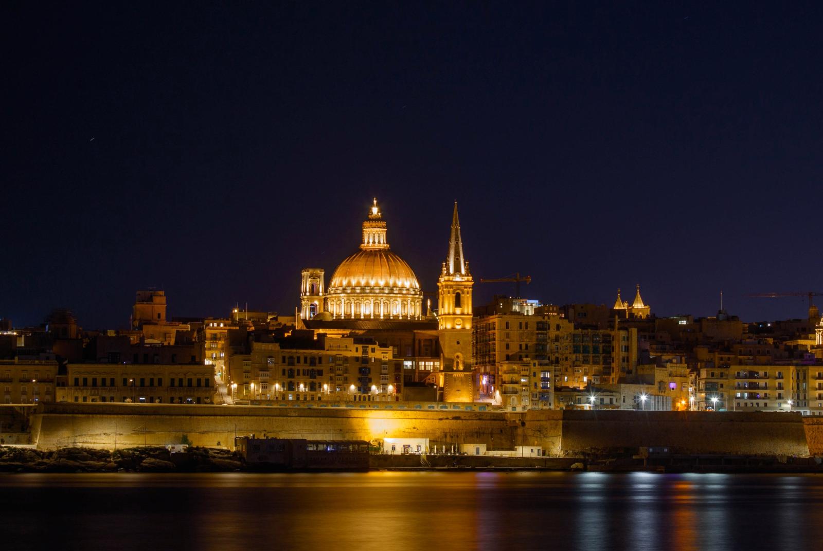 Wunderschöner Nachtblick auf die beleuchtete Skyline von Valletta, die unter klarem Himmel ikonische Wahrzeichen präsentiert.