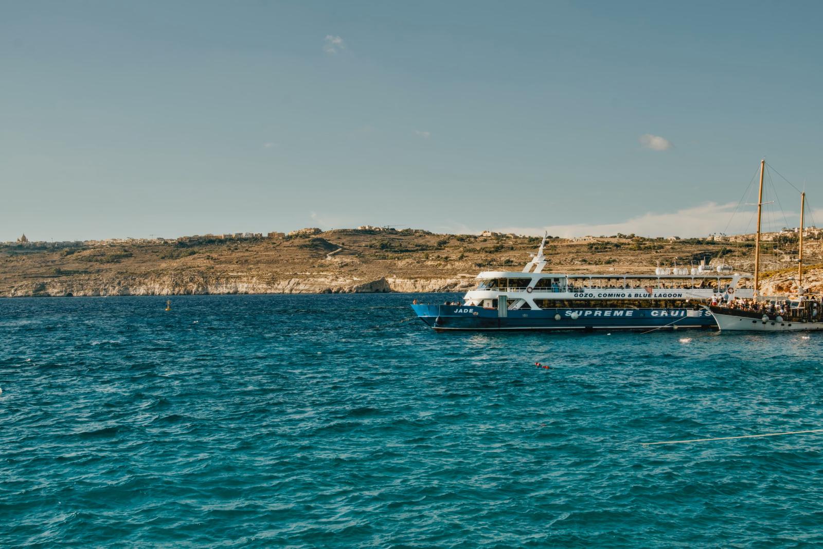 Ausflugsboot vor einer maltesischen Küste mit türkisblauem Wasser