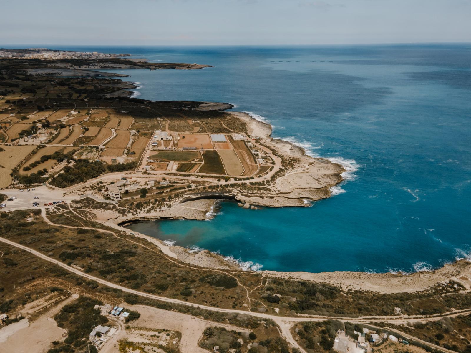 Beeindruckender Luftblick auf die Küste von Marsaxlokk mit klarem blauen Wasser und felsigen Küsten in Malta.