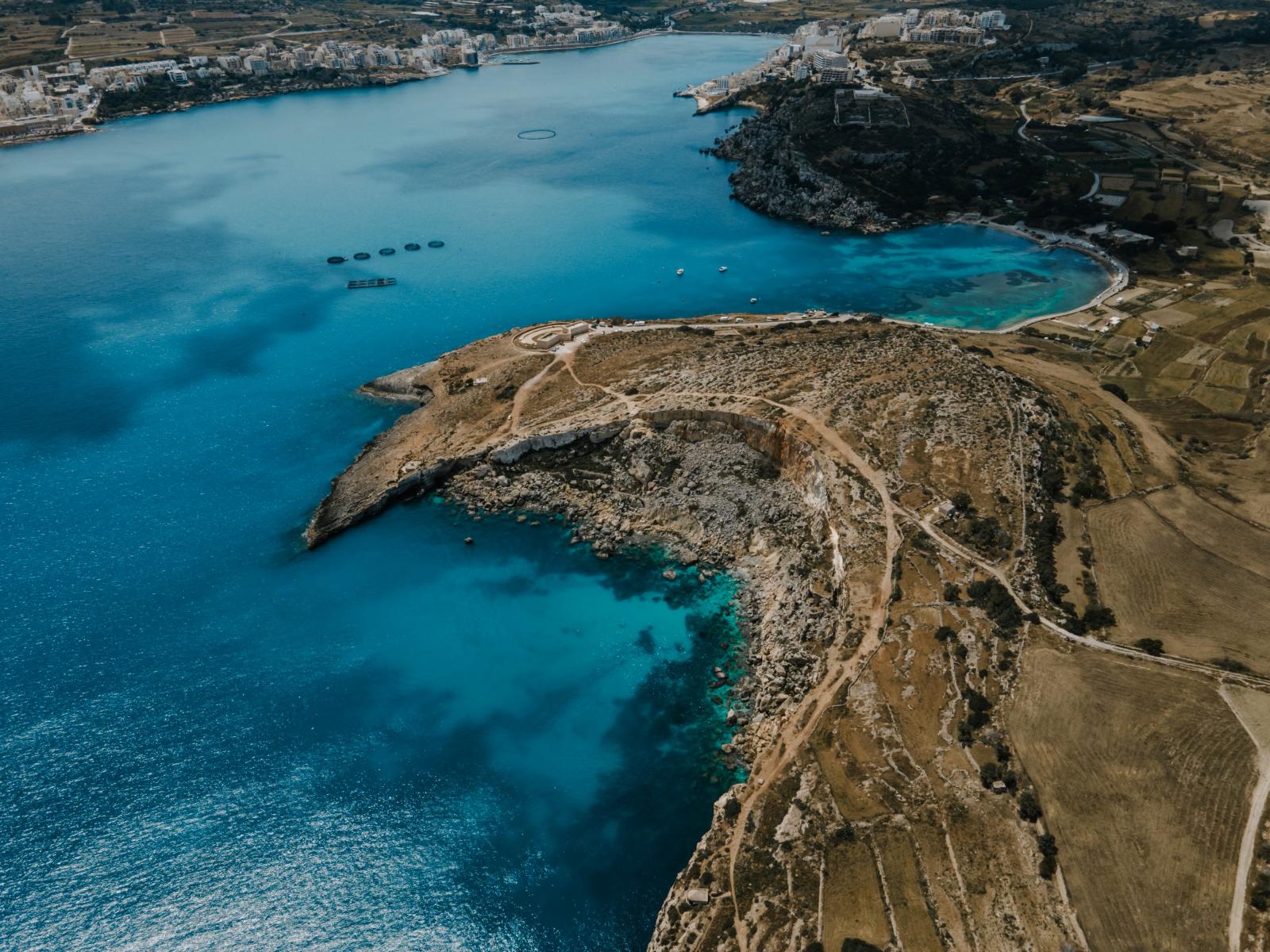 Erleben Sie den atemberaubenden Luftbildblick auf die Bucht von Mellieha in Malta mit kristallklarem, türkisfarbenem Wasser und rauer Küstenlinie.