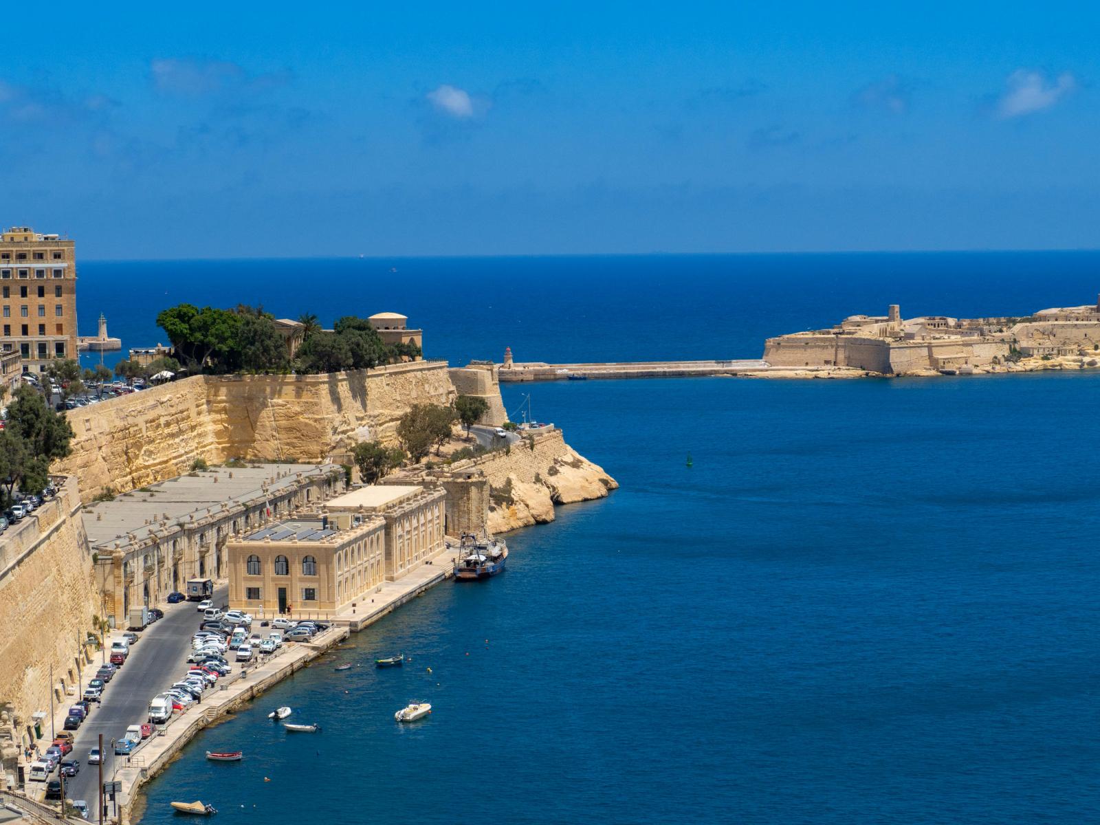 Panoramablick auf den Hafen von Valletta mit beeindruckenden Klippen, azurblauem Wasser und historischer Architektur.