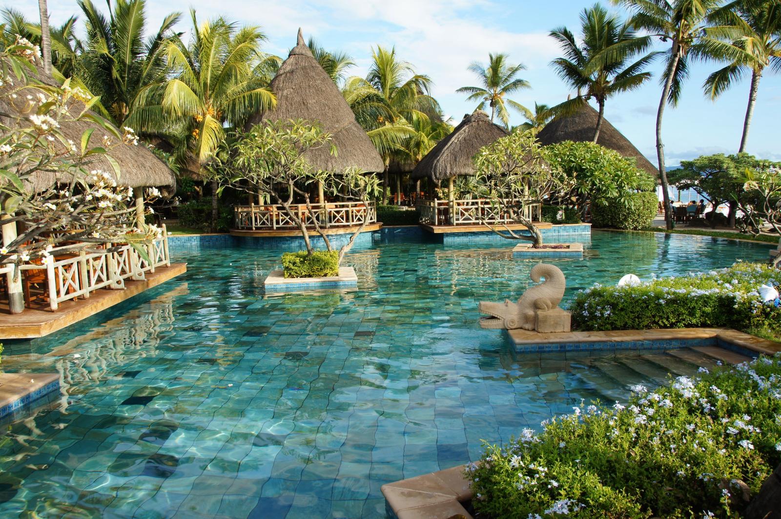 Familienfreundlicher Hotelpool mit Palmen und Blick auf die Lagune.