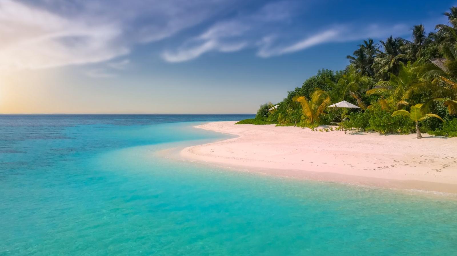 Heller Sandstrand an der Westküste von Mauritius mit Palmen und ruhigem Lagunenwasser.