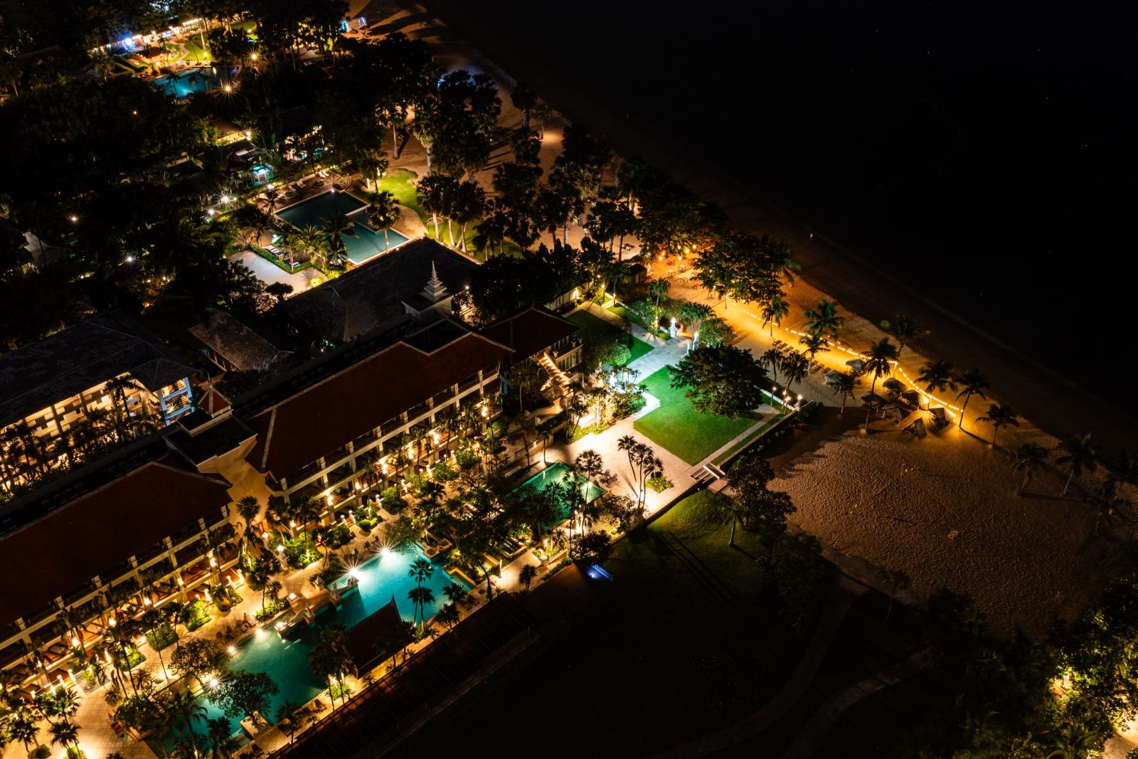 Gäste genießen den Abend auf der Terrasse eines tropischen Resorts mit Blick auf das Meer.