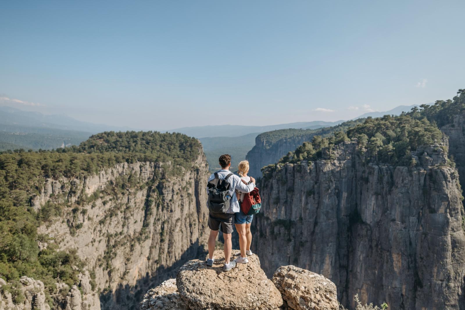 Reisepaar an einem Aussichtspunkt über einer beeindruckenden US-Landschaft