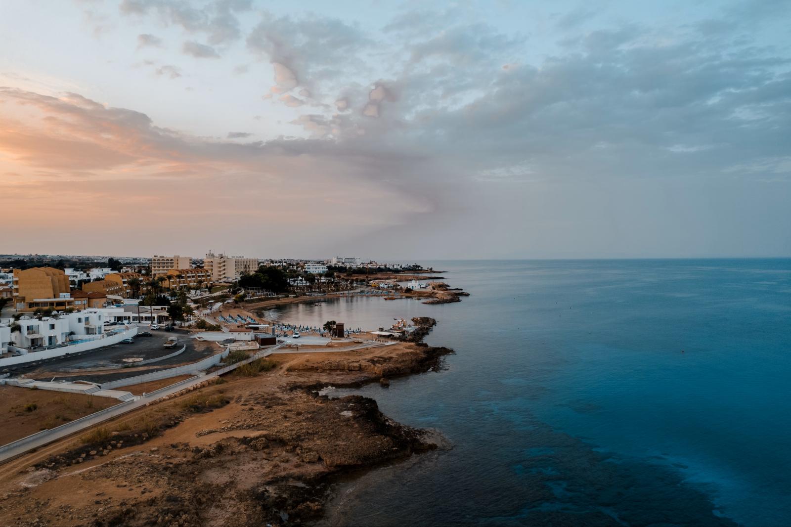 Sonnenuntergang an einem Sandstrand auf Zypern mit ruhigem Mittelmeer