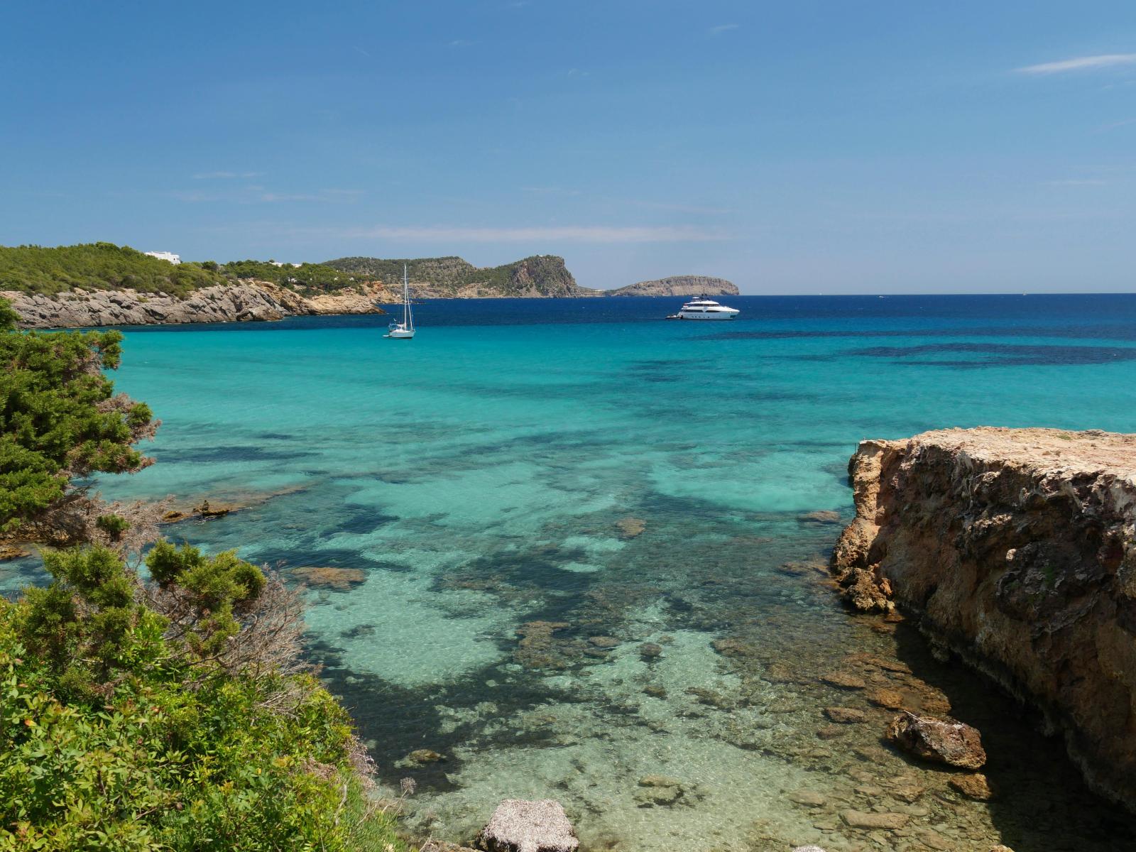 Bucht mit türkisblauem Meer und Booten auf Ibiza