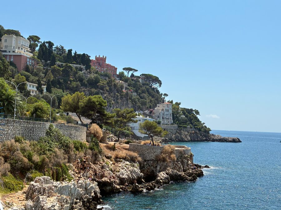 Felsige Küste am Sentier Littoral in Nizza mit Häusern am Hang und blauem Meer