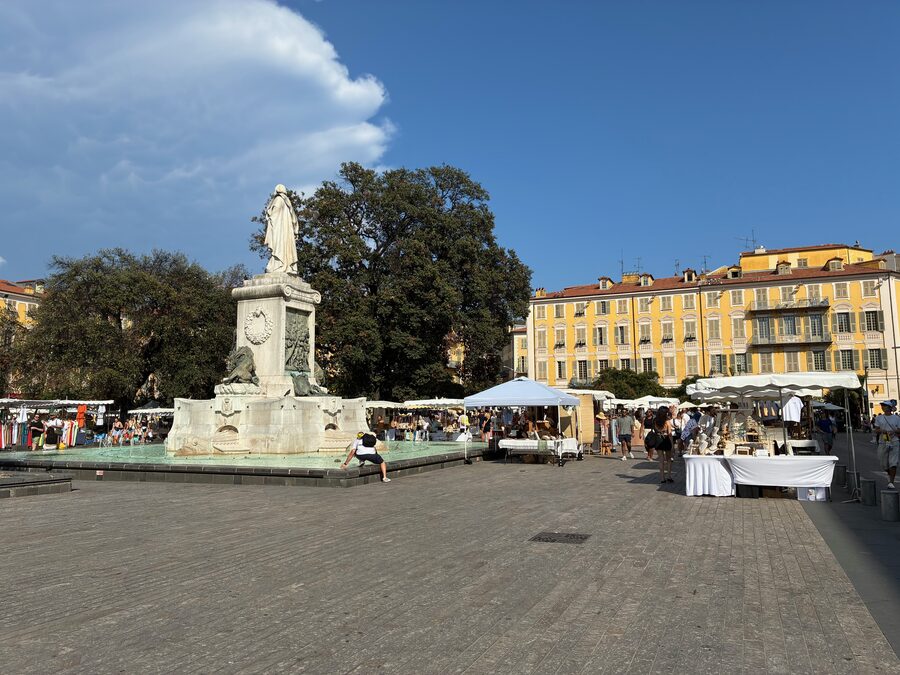 Die Place Garibaldi in Nizza mit dem Denkmal, gelben Fassaden und Marktständen