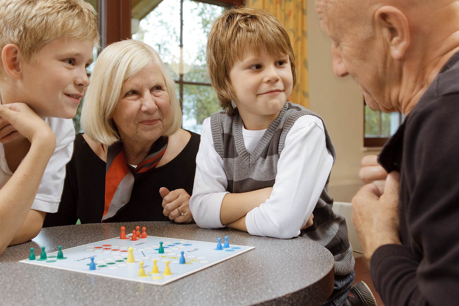 Zwei Jungs in Pullunder spielen Brettspiele mit ihren Großeltern, Oberlausitz © Rene Gaens